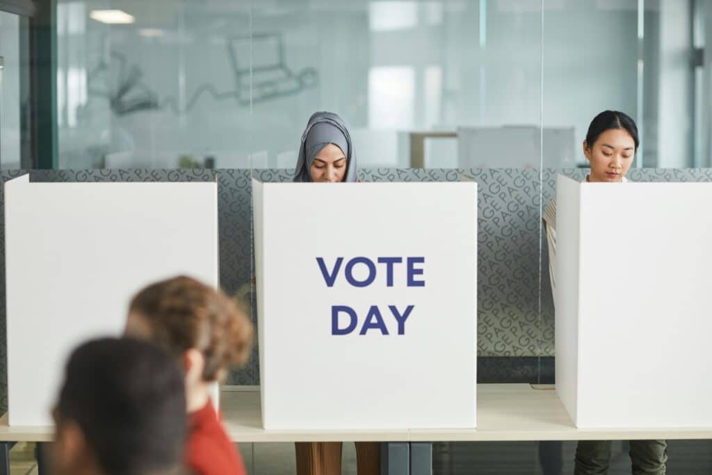 pexels-photo-7103107-7103107 Two women casting their votes in an office during election day, focusing on diversity and civic engagement.